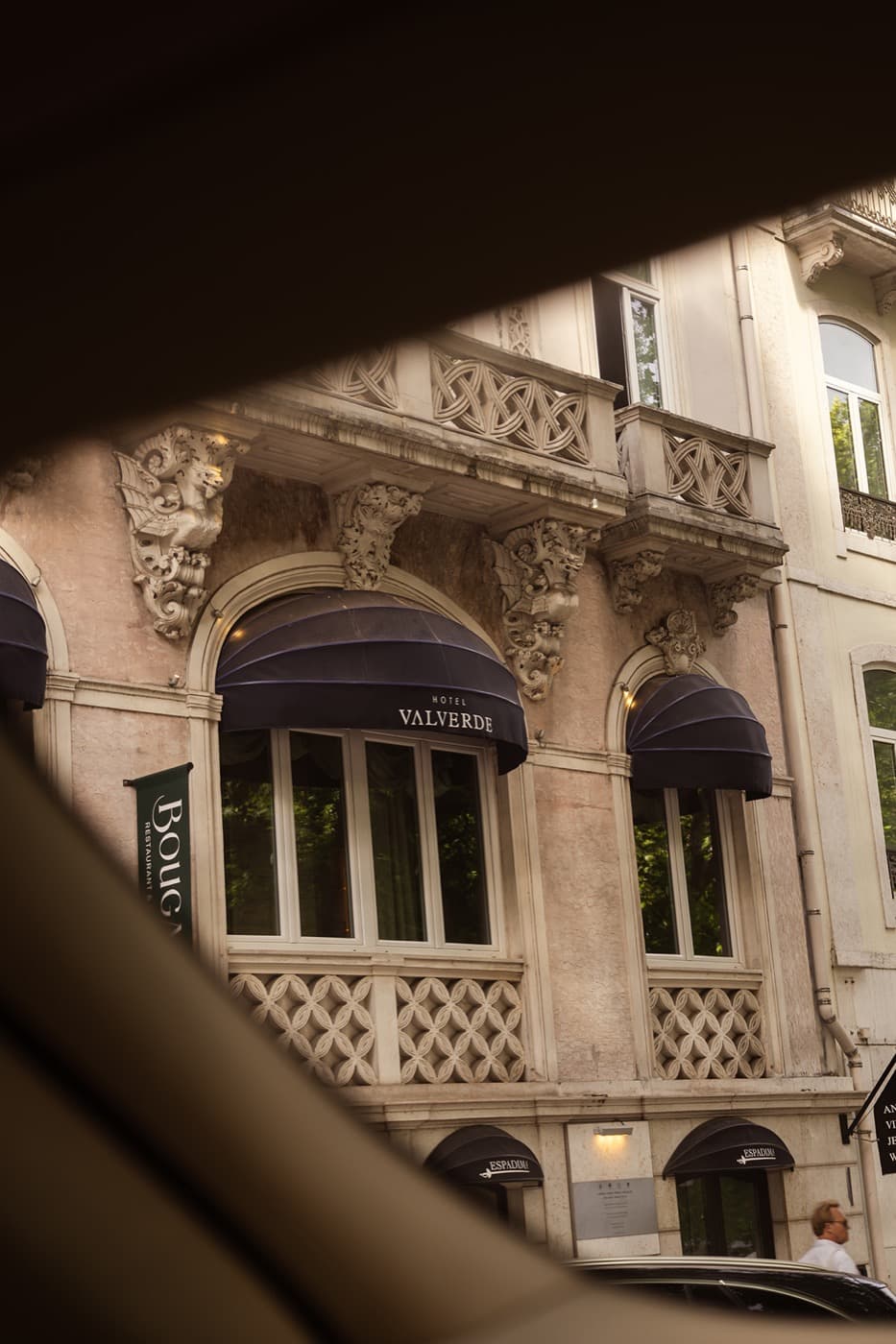 The house's façade glimpsed from a car window across the avenue.