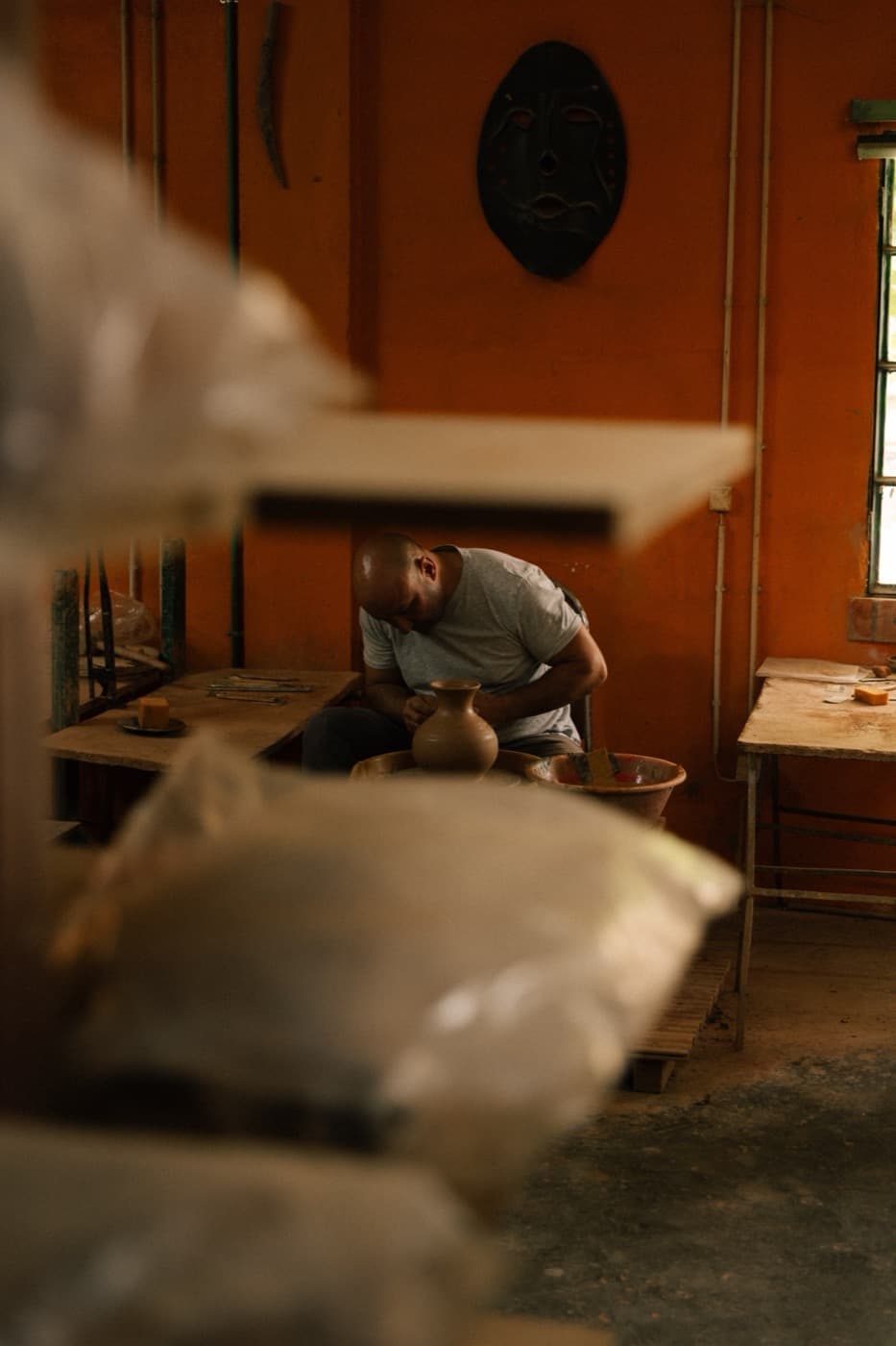 The potter at the wheel in the village workshop, a jug taking shape.