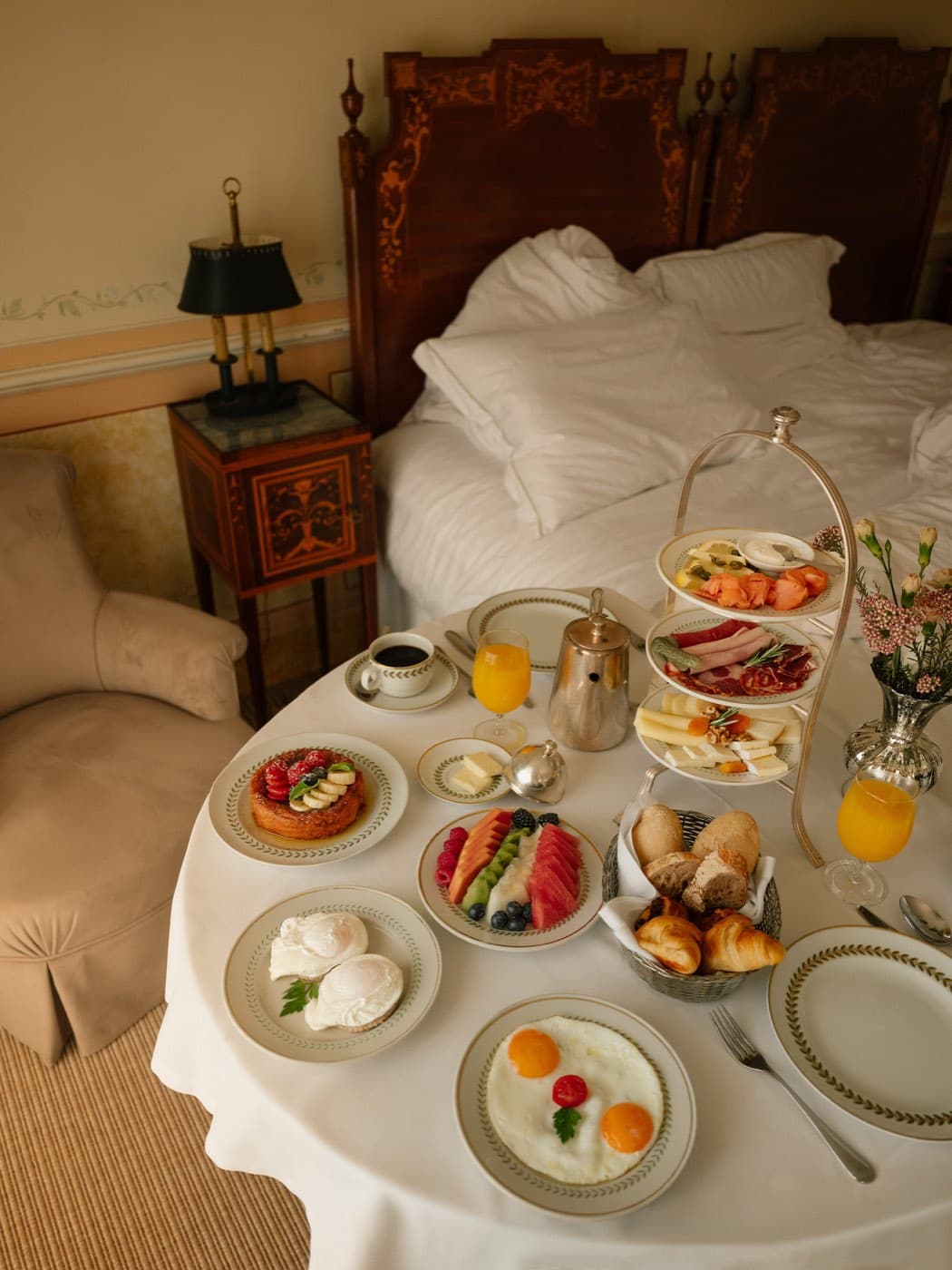 Breakfast brought to the room on a tray, small plates crowded across it.